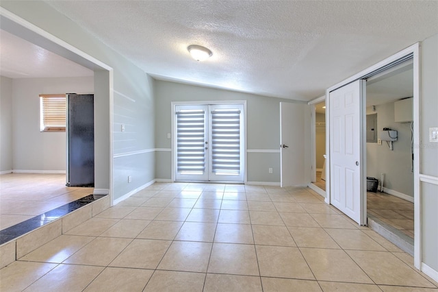 empty room with electric panel, light tile patterned floors, baseboards, and a textured ceiling