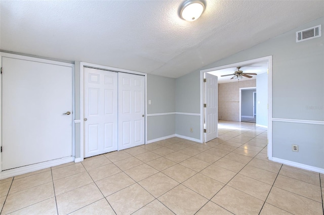 spare room featuring a ceiling fan, visible vents, light tile patterned flooring, vaulted ceiling, and a textured ceiling