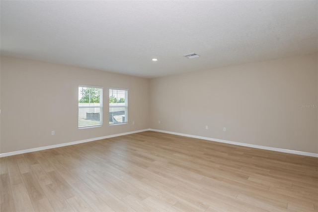 empty room with visible vents, baseboards, light wood-type flooring, and a textured ceiling