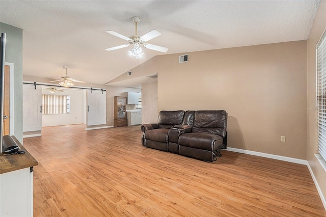 living area featuring a barn door, light wood-style floors, visible vents, and ceiling fan