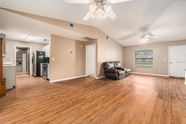 unfurnished room featuring visible vents, a ceiling fan, light wood finished floors, baseboards, and vaulted ceiling