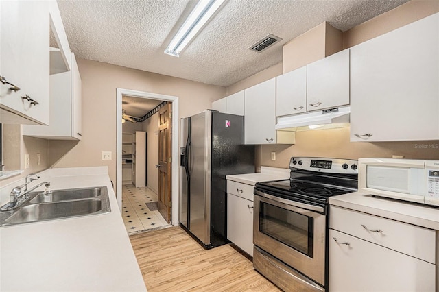 kitchen with visible vents, a sink, appliances with stainless steel finishes, under cabinet range hood, and white cabinetry