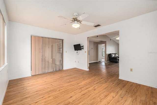 spare room featuring light wood finished floors, visible vents, baseboards, and ceiling fan