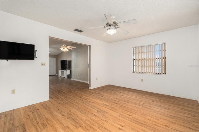 spare room with a textured ceiling, visible vents, light wood finished floors, and ceiling fan