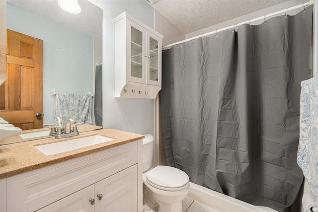 full bath featuring vanity, curtained shower, toilet, and a textured ceiling