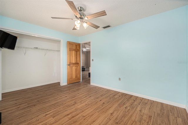 unfurnished bedroom with wood finished floors, visible vents, a closet, and a textured ceiling