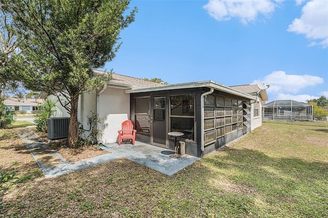 rear view of house with a patio, cooling unit, a yard, a sunroom, and stucco siding