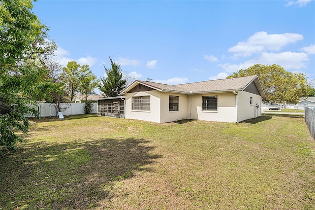 back of house with stucco siding, a lawn, and a fenced backyard