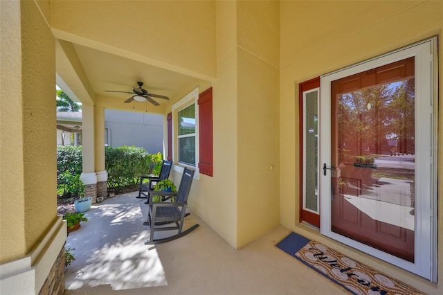 property entrance with stucco siding, a porch, and a ceiling fan