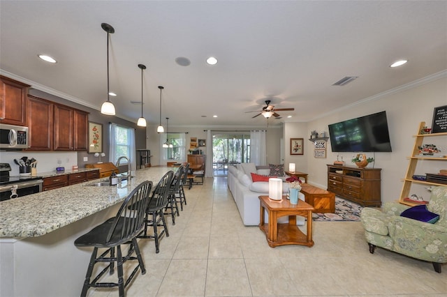 living area with visible vents, plenty of natural light, a ceiling fan, and ornamental molding