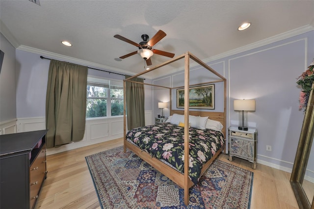 bedroom featuring a textured ceiling, a decorative wall, light wood-style flooring, and ornamental molding