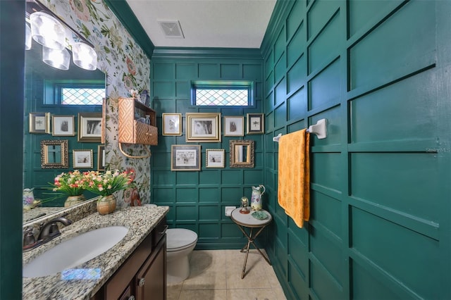 half bathroom with vanity, visible vents, ornamental molding, tile patterned floors, and toilet