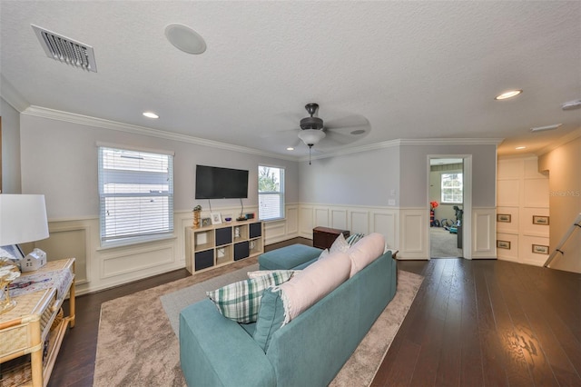 living area with visible vents, a wainscoted wall, a textured ceiling, ceiling fan, and dark wood-style flooring