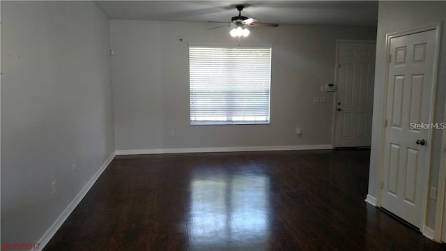 empty room with dark wood finished floors, a ceiling fan, and baseboards