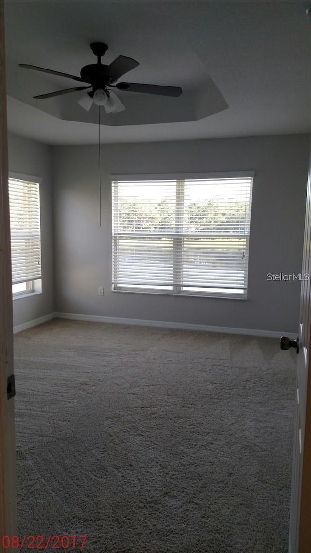 unfurnished room featuring baseboards, carpet, a tray ceiling, and a ceiling fan