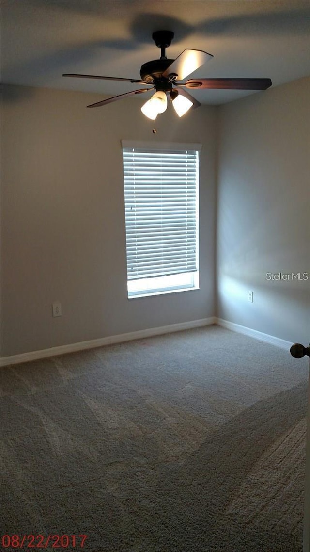 carpeted empty room featuring baseboards and ceiling fan