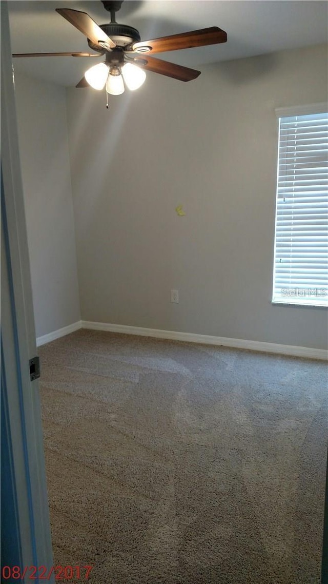 empty room featuring carpet, baseboards, and ceiling fan