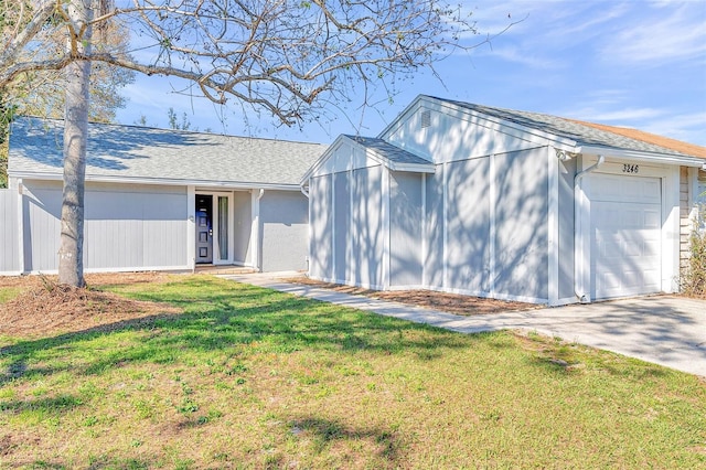 view of front of house featuring a garage, concrete driveway, a front yard, and roof with shingles