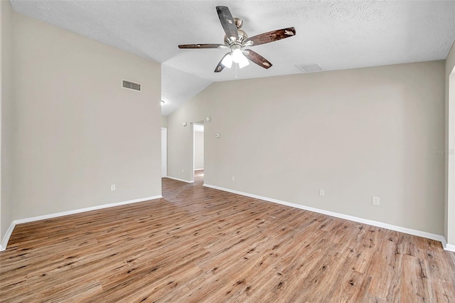 empty room featuring light wood-type flooring, visible vents, a ceiling fan, baseboards, and vaulted ceiling