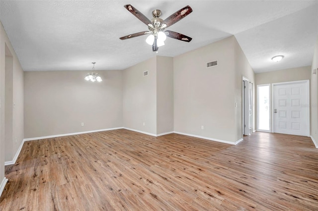 unfurnished room featuring visible vents, baseboards, lofted ceiling, light wood-style floors, and ceiling fan with notable chandelier