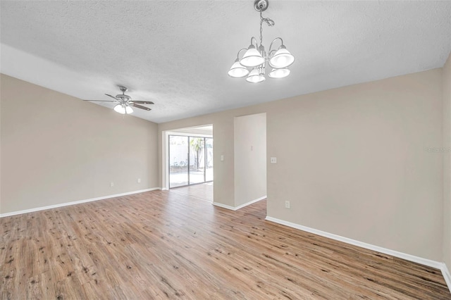 empty room featuring light wood finished floors, ceiling fan with notable chandelier, a textured ceiling, and baseboards