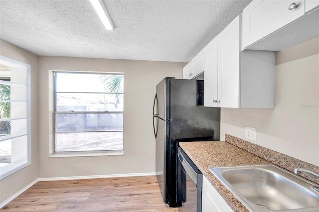 kitchen with light wood finished floors, dishwashing machine, white cabinets, a textured ceiling, and a sink