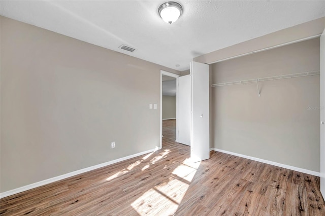 unfurnished bedroom featuring baseboards, visible vents, light wood finished floors, a closet, and a textured ceiling