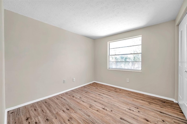 unfurnished bedroom featuring a closet, baseboards, a textured ceiling, and wood finished floors