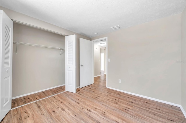 unfurnished bedroom featuring light wood finished floors, visible vents, baseboards, a closet, and a textured ceiling