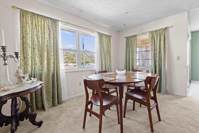 dining area featuring baseboards, light colored carpet, and a textured ceiling
