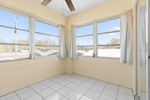 unfurnished room with ceiling fan, light tile patterned flooring, and wood walls