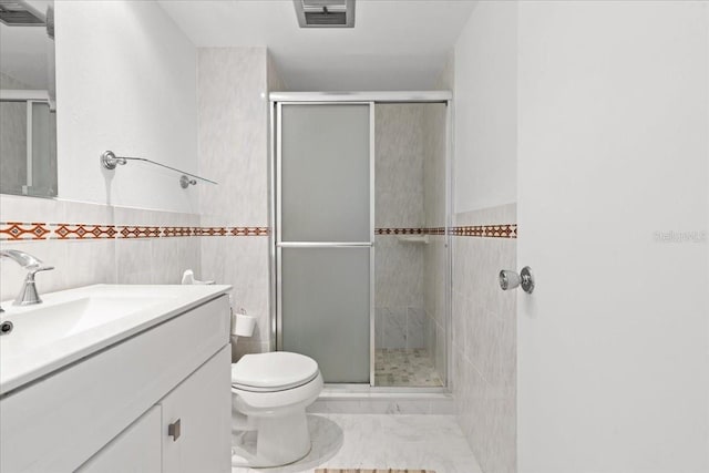 bathroom with vanity, visible vents, a shower stall, tile walls, and toilet