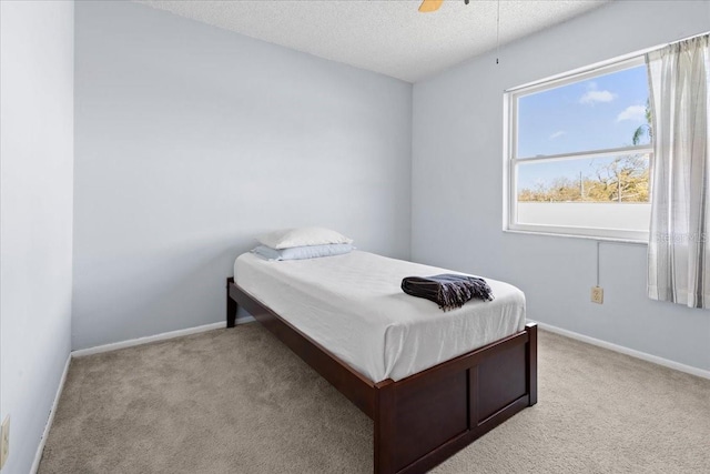bedroom with light colored carpet, a textured ceiling, and baseboards