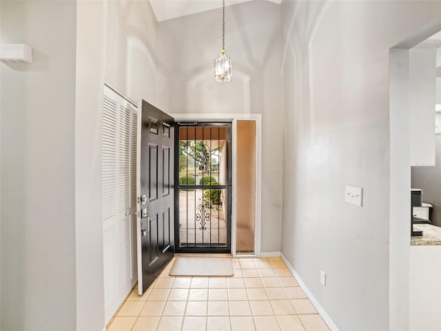 entrance foyer featuring light tile patterned floors, baseboards, and a towering ceiling