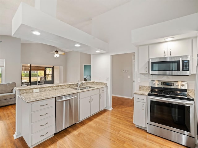 kitchen featuring tasteful backsplash, open floor plan, vaulted ceiling, a peninsula, and stainless steel appliances