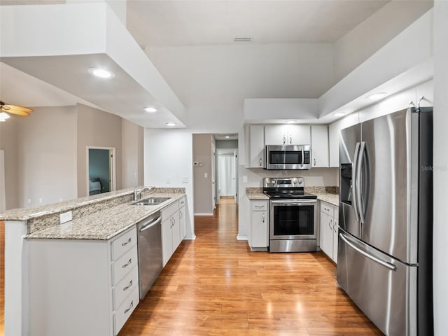 kitchen featuring a peninsula, light wood-style flooring, white cabinets, and stainless steel appliances