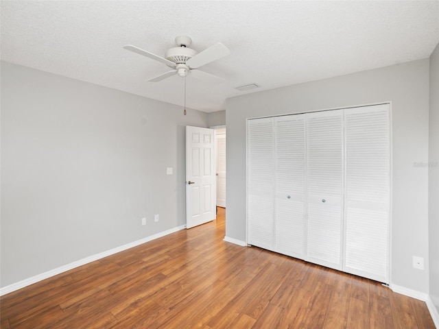 unfurnished bedroom featuring a closet, ceiling fan, baseboards, and wood finished floors