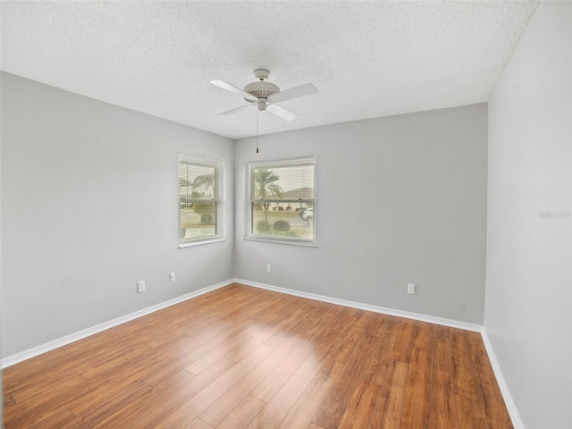 unfurnished room with a textured ceiling, a ceiling fan, baseboards, and wood finished floors