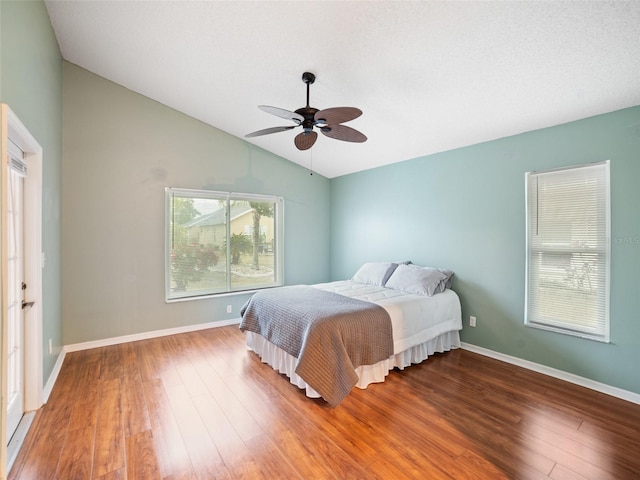 bedroom with baseboards, lofted ceiling, wood finished floors, and a ceiling fan