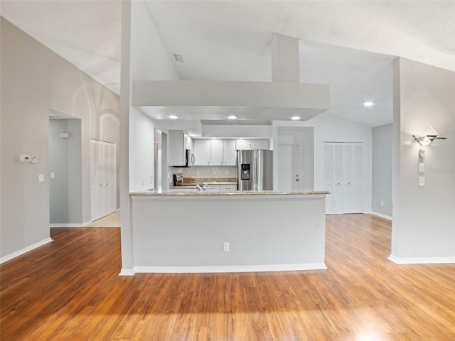 kitchen featuring light wood finished floors, decorative backsplash, a peninsula, and stainless steel appliances