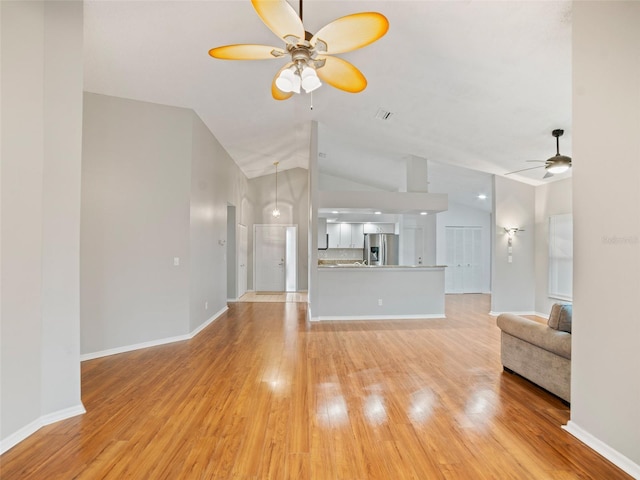 unfurnished living room with light wood finished floors, baseboards, ceiling fan, and vaulted ceiling