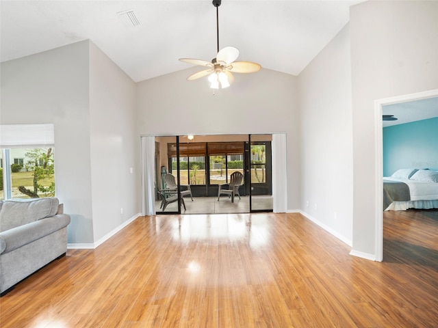 living area with visible vents, baseboards, high vaulted ceiling, and wood finished floors