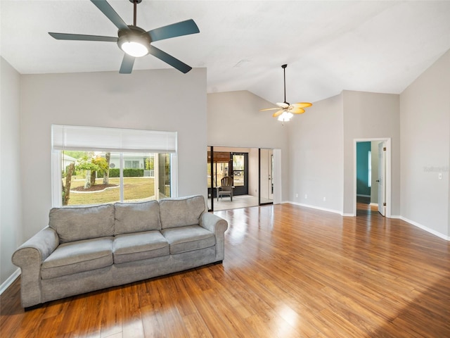 living room with ceiling fan, baseboards, high vaulted ceiling, and wood finished floors