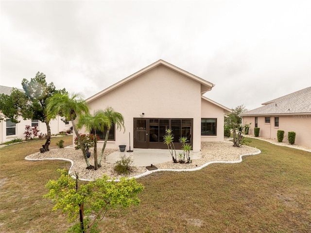 back of property featuring a patio area, a lawn, and stucco siding