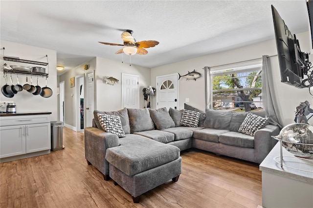 living area with ceiling fan, light wood-style flooring, and a textured ceiling