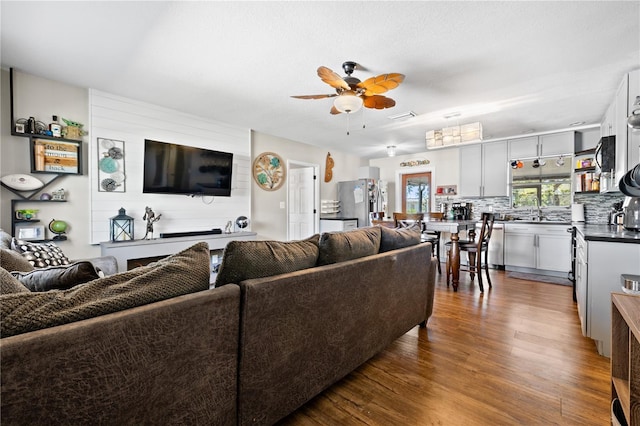 living area featuring ceiling fan, visible vents, and dark wood finished floors