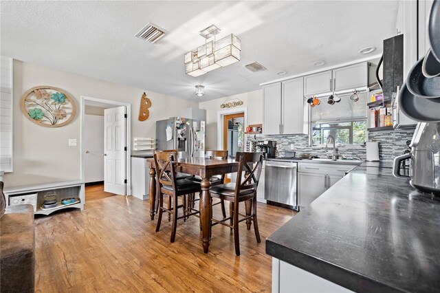 kitchen featuring visible vents, backsplash, light wood-type flooring, appliances with stainless steel finishes, and a sink