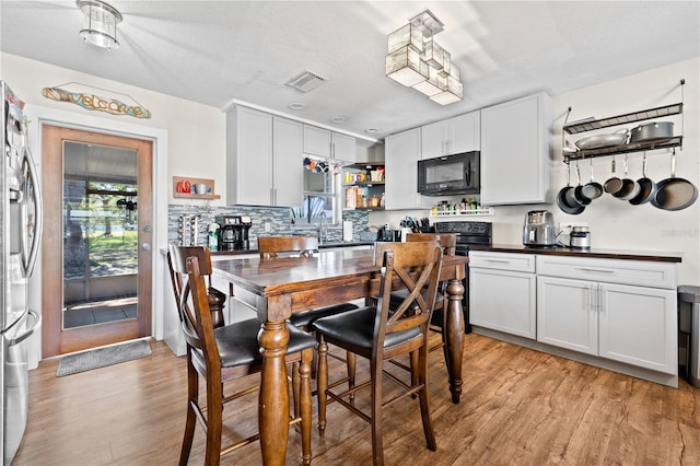 kitchen with visible vents, open shelves, decorative backsplash, black appliances, and light wood-type flooring