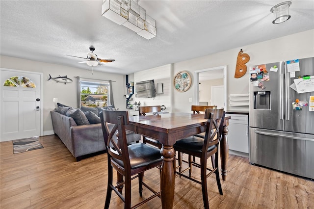 dining area with light wood-style flooring and a textured ceiling