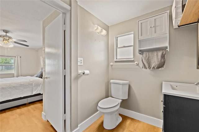 ensuite bathroom featuring wood finished floors, baseboards, ceiling fan, ensuite bathroom, and toilet